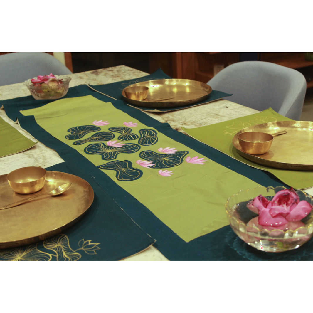 Decorative table setting with green placemats featuring floral designs, gold plates, and pink flowers.