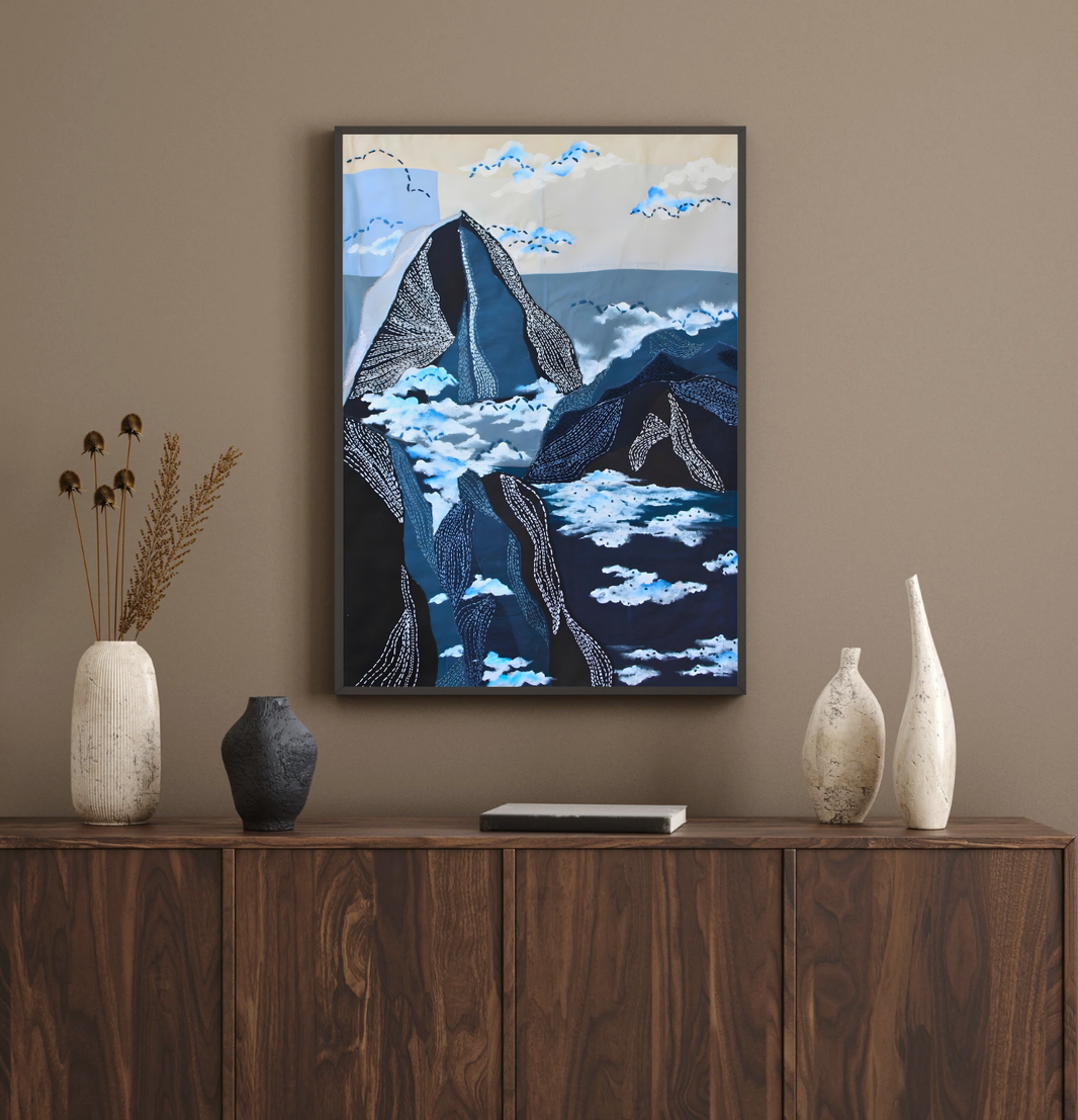 Framed mountain inspired artwork on a wall above a wooden cabinet with decorative vases.