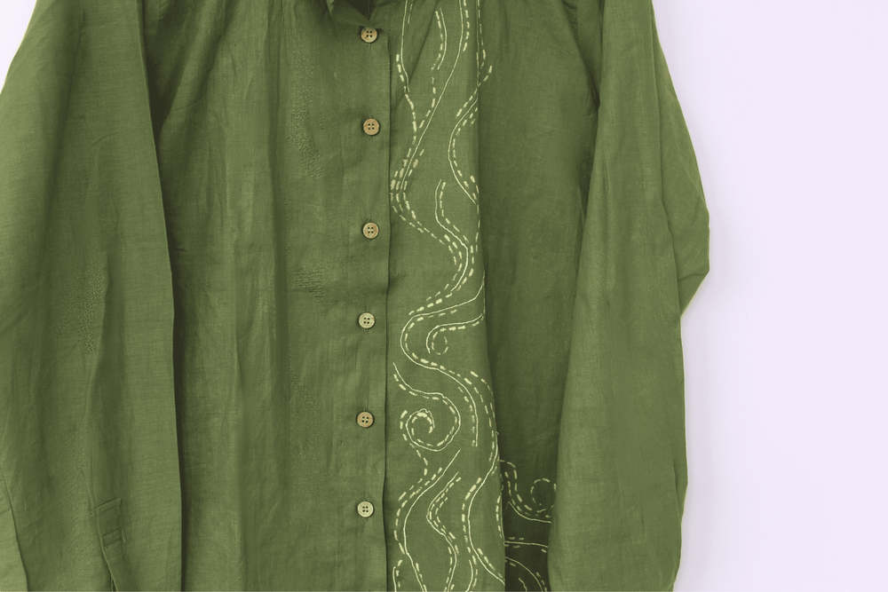 Green shirt with intricate white embroidery on a white background