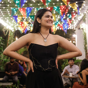 Black strapless corset top with minimal gold artwork, modern party top styled for evening celebrations.