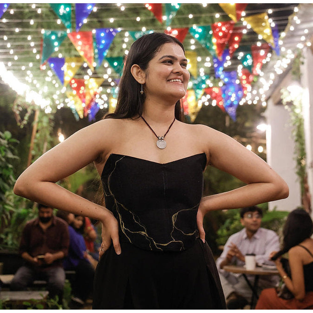 Black strapless corset top with minimal gold artwork, modern party top styled for evening celebrations.