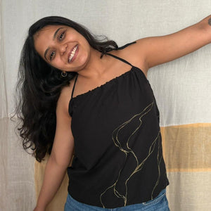 Woman wearing a black top with gold designs and blue jean