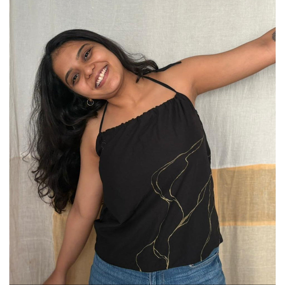 Woman wearing a black top with gold designs and blue jean
