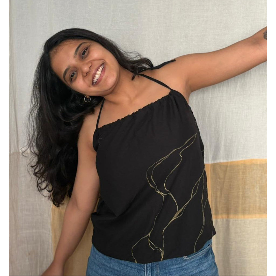 Woman wearing a black top with gold designs and blue jean