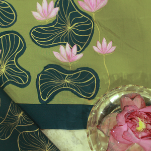 Green fabric with pink floral hand painting and a pink flower in a glass dish.