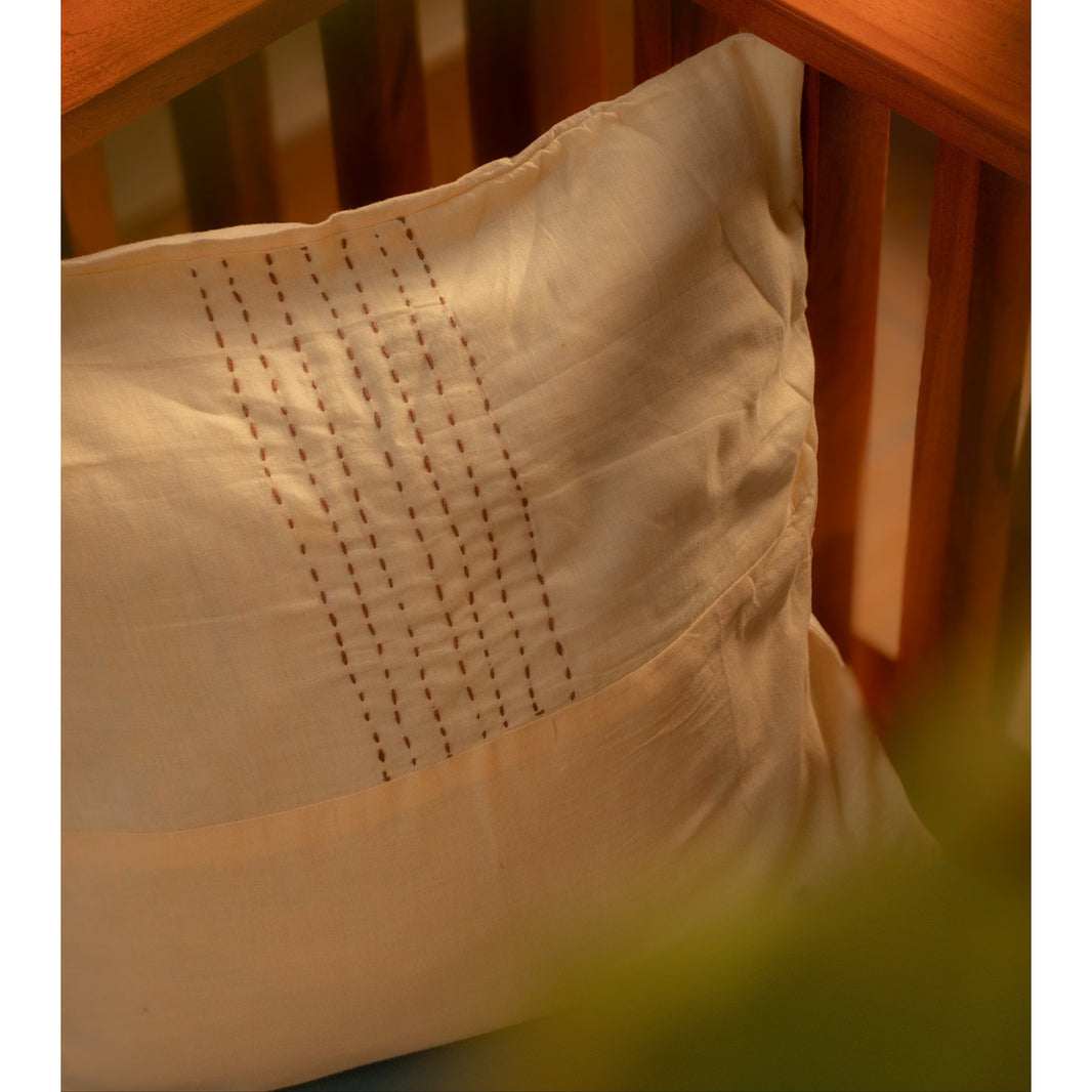 Close-up of a wooden swing with a white and beige pillow featuring intricate stitching.