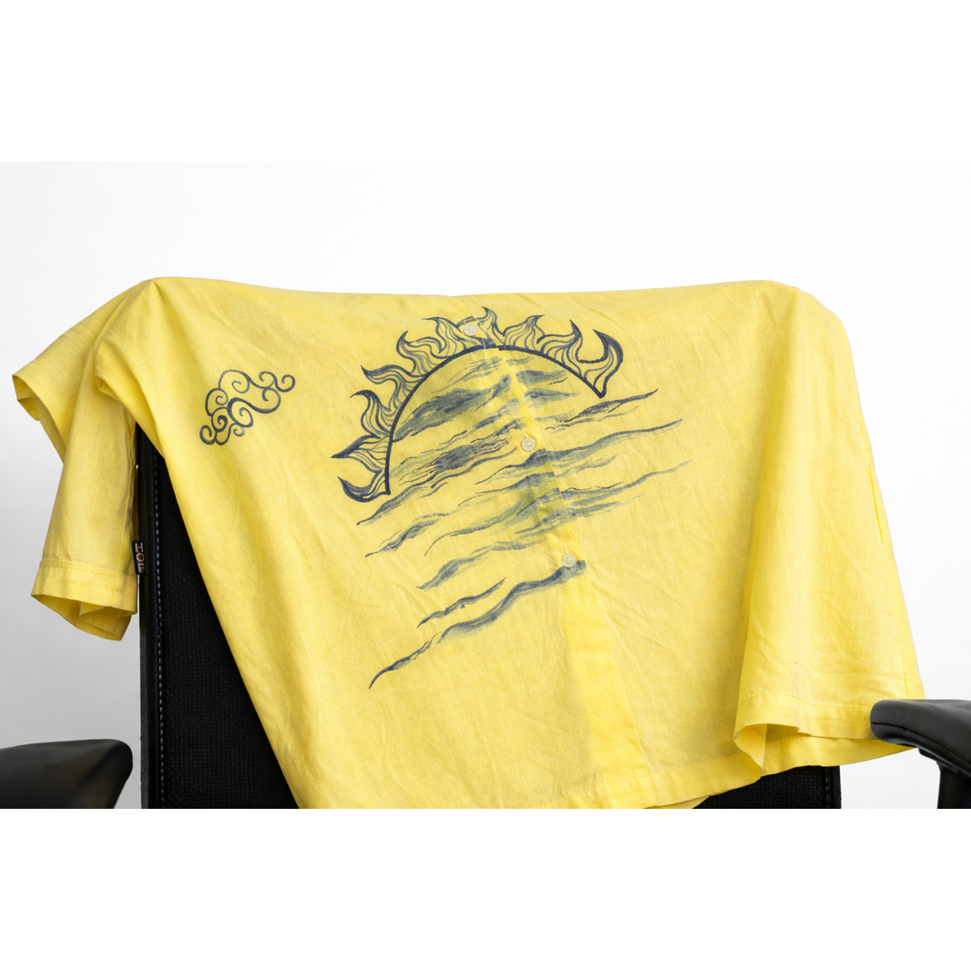 Close-up detail of the hand-painted sun and wave motif on JOD's yellow cotton Lime Shirt