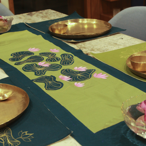 Decorative table setting with green placemats featuring floral designs, gold plates, and pink flowers.