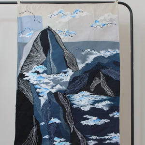 Large handcrafted textile wall art with layered landscape shapes and cloud textures, modern wall decor for living room interiors and workspaces.