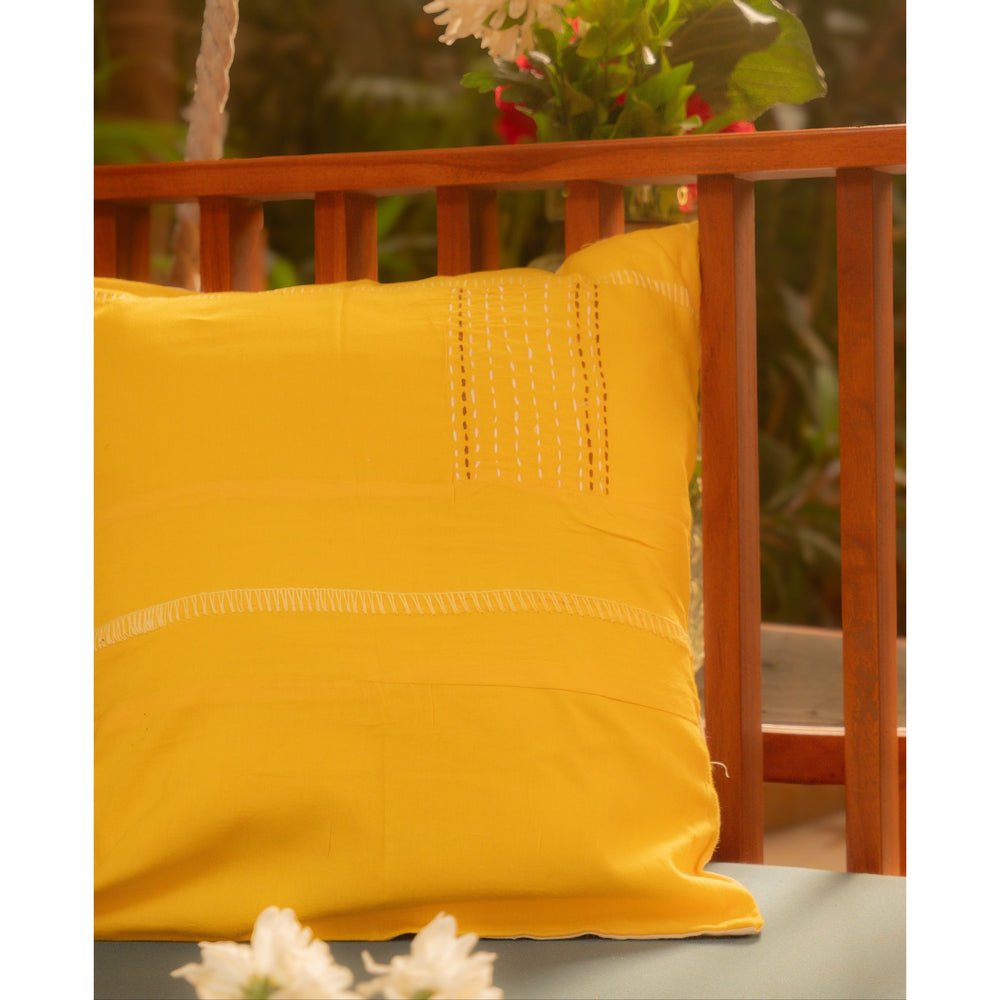 Yellow pillow on a wooden swing with greenery in the background