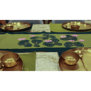 Decorative table setting with gold bowls and a green tablecloth featuring floral patterns.