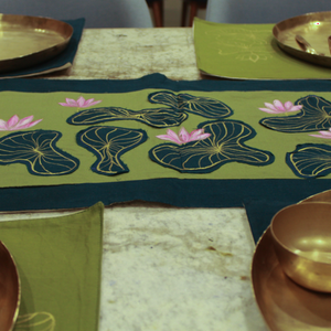 Decorative table setting with gold bowls and a green tablecloth featuring floral patterns.