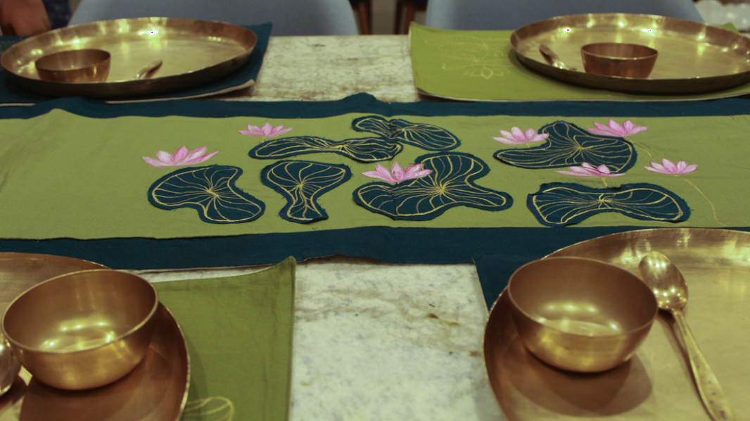 Decorative table setting with gold bowls and a green tablecloth featuring floral patterns.
