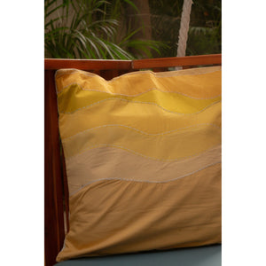 Yellow quilted pillow on a wooden chair with plants in the background