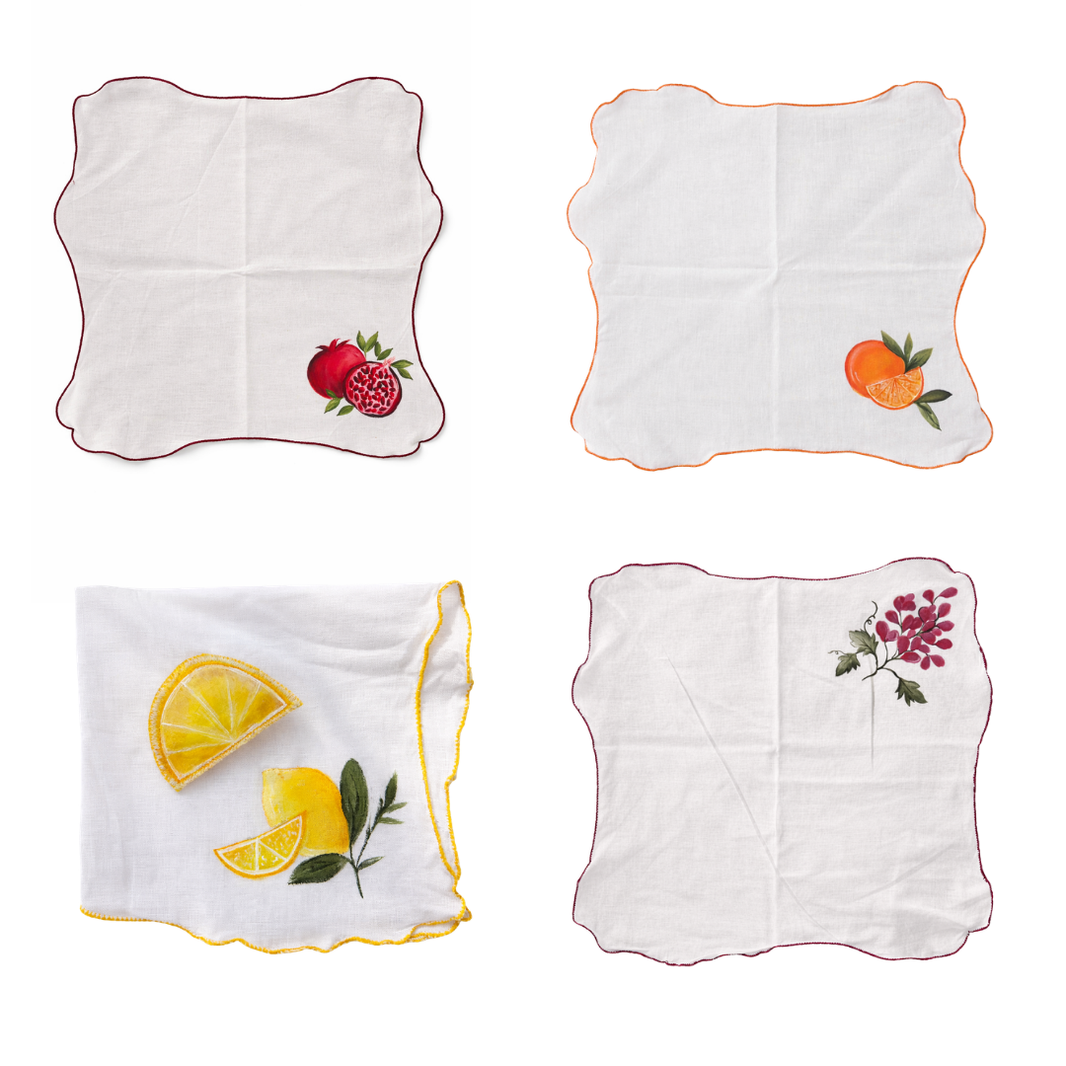 Four hand painted table napkins with fruit designs on a white background