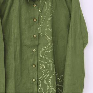 Green shirt with intricate white embroidery on a white background
