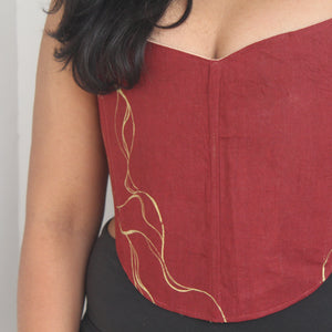 Red strapless top with gold accents worn by a person against a neutral background