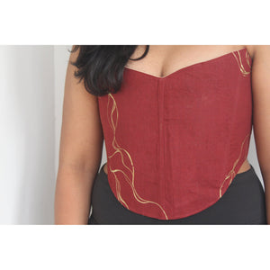 Red strapless top with gold accents worn by a person against a neutral background