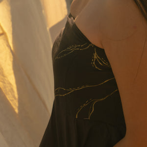 Person wearing a black Top top with gold detailing