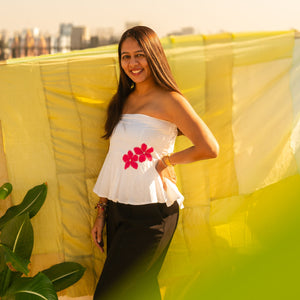 Woman wearing a floral strapless peplum top with hand crafted flower detail, lightweight summer tube top for casual and vacation wear.