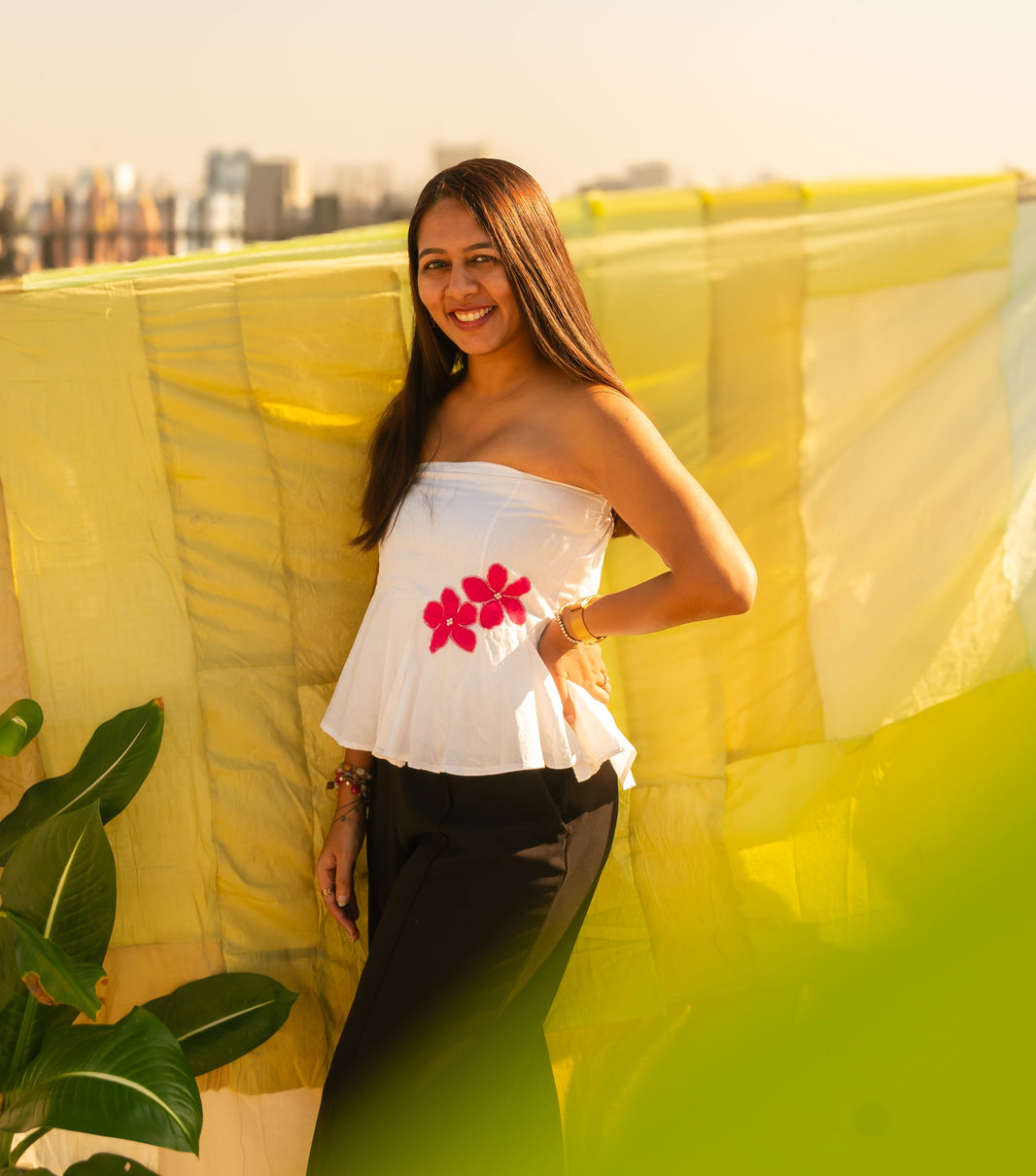 Woman wearing a floral strapless peplum top with hand crafted flower detail, lightweight summer tube top for casual and vacation wear.