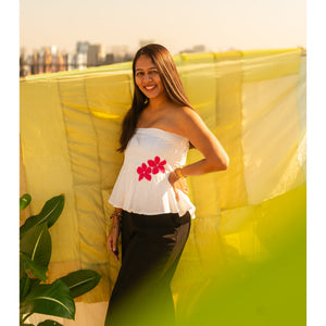 Woman wearing a floral strapless peplum top with hand crafted flower detail, lightweight summer tube top for casual and vacation wear.