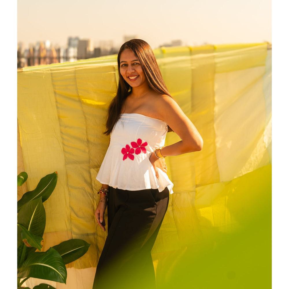 Woman wearing a floral strapless peplum top with hand crafted flower detail, lightweight summer tube top for casual and vacation wear.
